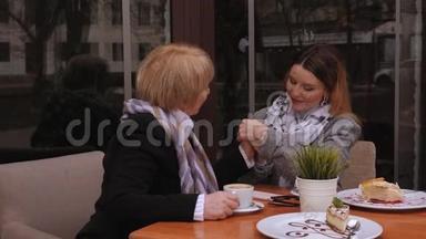 一位年迈的母亲和一个女儿在咖啡馆里，女儿牵着母亲`手